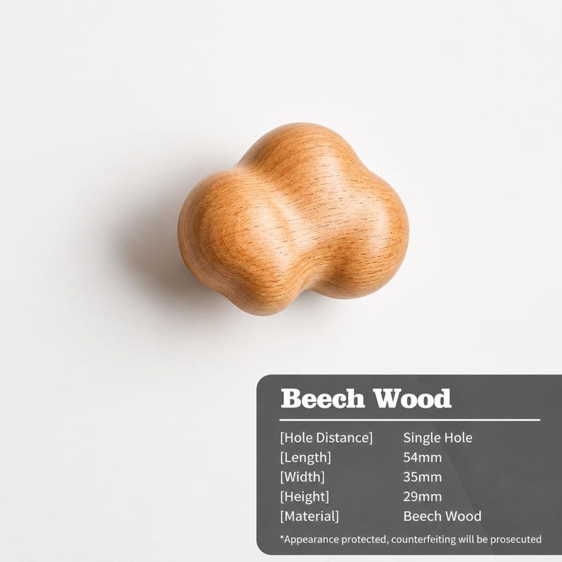 Peut inclure: Un bouton de meuble en forme de nuage en bois de h&ecirc;tre brun clair avec une surface lisse et arrondie. Le texte indique qu'il est en bois de h&ecirc;tre, poss&egrave;de un trou unique et mesure 54 mm de longueur, 35 mm de largeur et 29 mm de hauteur.