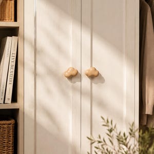 Peut inclure: Deux boutons de placard en bois clair en forme de nuages sont fix&eacute;s au centre d'une paire de portes de placard verticales &agrave; panneaux blanc cass&eacute;. Les boutons ont une finition lisse et arrondie et sont plac&eacute;s c&ocirc;te &agrave; c&ocirc;te sur les portes.