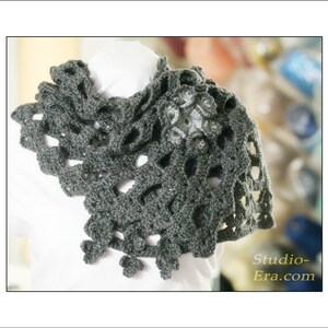 May include: A gray crocheted shawl with a floral design and openwork pattern. The shawl is draped over a white surface. The text "Studio-Era.com" is visible in the lower right corner.