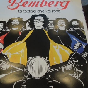 Pu&ograve; includere: Un poster vintage che pubblicizza il tessuto Bemberg con lo slogan "la fodera che va forte". Il poster presenta un gruppo di uomini con occhiali da sole che guidano motociclette. Gli uomini indossano giacche di pelle nere con accenti gialli, rossi e blu. Il poster ha un'estetica retr&ograve; degli anni '70.