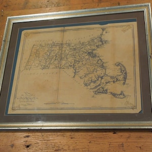 May include: A framed antique map of the state of Massachusetts. The map is printed on aged paper and shows the state's borders, major cities, and towns. The map is titled "A Map of the State of Massachusetts" and is dated 1795.