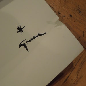 Pu&ograve; includere: Una firma in bianco e nero con il nome "Trueman" scritto in corsivo. Una piccola stella &egrave; sopra la firma.