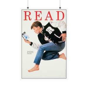 May include: A poster featuring the word READ in large red letters at the top. A person is jumping while wearing a black and white varsity jacket with the letter R, blue jeans, and no shoes. They hold a book. Text reads David Bowie for America's Libraries.