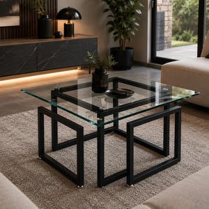 Peut inclure: Une table basse carrée dotée d'un plateau en verre transparent reposant sur une structure en métal noir. La base est composée de quatre pieds métalliques carrés interconnectés formant une structure géométrique solide pour le plateau.