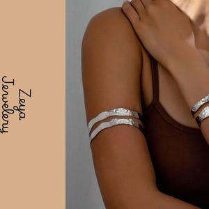 May include: Two silver-toned arm cuffs and two silver-toned wrist bracelets with a hammered, textured finish. The jewelry features an irregular, organic shape. The text Zeya Jewellery is printed vertically on the left side of the image.