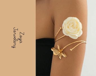 Pulseira de braço aberta com detalhes florais dourados e rosa branca