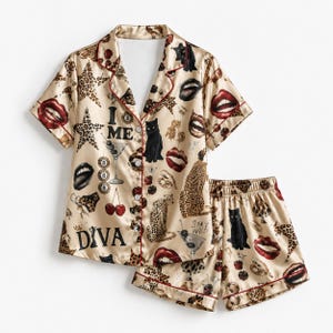 Può includere: Un set di pigiama color champagne composto da una camicia a maniche corte con bottoni e pantaloncini abbinati. Il tessuto presenta una stampa di gatti neri, macchie di leopardo, labbra rosse, ciliegie, bicchieri da martini e il testo "I ME", "DIVA" e "STAY WILD".