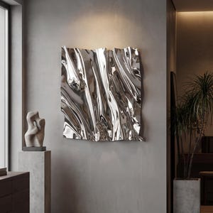 Könnte beinhalten: Eine quadratische Wandskulptur mit einer hochglänzenden, polierten Chromoberfläche mit tiefen, wellenförmigen Falten und Rippeln, die ein flüssiges Aussehen erzeugen. Die Metallplatte wird von oben beleuchtet und wirft sanfte Lichtreflexe.