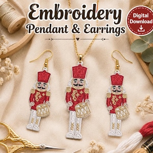 Op de afbeelding: Een sieradenset bestaande uit een hanger en twee oorbellen, elk in de vorm van een notenkraker-soldaat met rood, wit en goud borduurwerk. De hanger hangt aan een gouden ketting. De tekst "Embroidery Pendant & Earrings" is in de afbeelding zichtbaar.