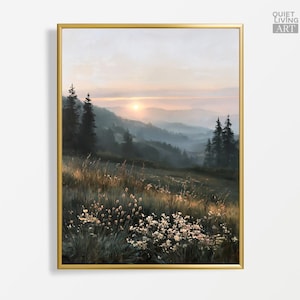 Könnte beinhalten: Ein vertikaler, rechteckiger Kunstdruck in einem goldenen Rahmen, der eine neblige Berglandschaft bei Sonnenaufgang zeigt. Im Vordergrund befindet sich ein Feld mit hohem Gras und kleinen weißen Wildblumen, während dunkle Nadelbäume aufragen.