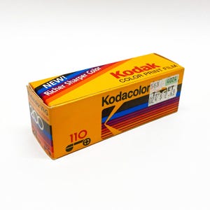 May include: A rectangular yellow box of Kodak Kodacolor VR-G 200 color print film for 110 cameras. The packaging features red, blue, and purple stripes, the text NEW! Richer Sharper Color, and a white price sticker with the text 563 4024 TARGET 024 $ 2.49.
