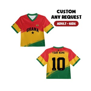 May include: A short-sleeved V-neck jersey featuring the colors red, yellow, and green with a brushstroke design. The front displays the text GHANA and a small flag. The back shows the text YOUR NAME and the number 10. Text reads CUSTOM ANY REQUEST.