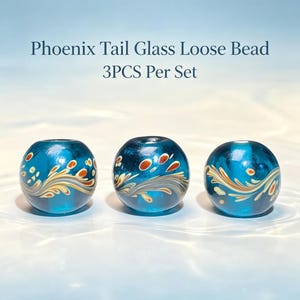 May include: Three round, translucent teal glass beads with a Phoenix Tail pattern featuring swirling white and tan lines accented by small orange dots. The text Phoenix Tail Glass Loose Bead 3PCS Per Set is displayed above the beads.