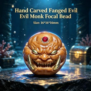 May include: A hand carved fanged evil monk focal bead with a brown finish, featuring a red gemstone on the forehead and gold-colored fangs. The bead measures 16 by 16 by 16 millimeters. The text Hand Carved Fanged Evil Evil Monk Focal Bead is visible.