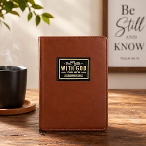 May include: A brown, rectangular, leather-like devotional book with a black and gold rectangular label on the front cover. The label features the text "One Minute WITH GOD FOR MEN 366 DAILY DEVOTIONS" in a clean, sans-serif font style.