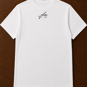 Pode incluir: Uma t-shirt branca de manga curta com um pequeno log&oacute;tipo gr&aacute;fico preto centrado na parte superior do peito. O log&oacute;tipo consiste numa escrita cursiva estilizada sobre o texto JOMO numa fonte sem serifa limpa e simples.