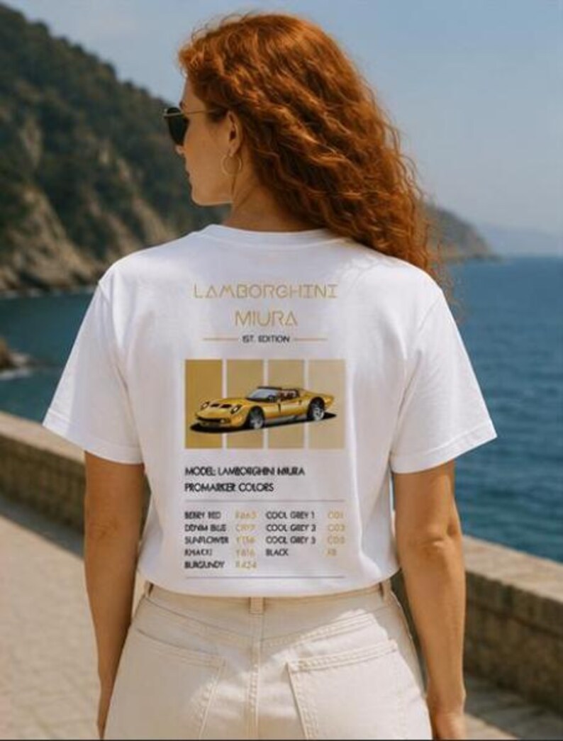 Pode incluir: Uma t-shirt branca de manga curta com um gr&aacute;fico nas costas contendo o texto Lamborghini Miura 1st Edition, uma ilustra&ccedil;&atilde;o de um carro desportivo amarelo e uma lista de cores Promarker incluindo Berry Red, Denim Blue, Sunflower, Khaki e Burgundy.