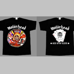 Peut inclure: Deux t-shirts noirs à manches courtes. Le t-shirt de gauche présente un graphique circulaire avec le texte "motörhead" et "1916" au-dessus d'une illustration de guerre. Celui de droite affiche "motörhead" au-dessus de cartes à jouer.
