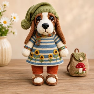 Könnte beinhalten: Eine gehäkelte Beagle-Puppe mit einer grünen Strickmütze mit Bommel, einem blau-weiß gestreiften Pullover mit Sonnenblumenstickerei, orangefarbener Leggings und braunen Sandalen. Ein kleiner beiger Rucksack mit rotem Pilzmotiv steht daneben.
