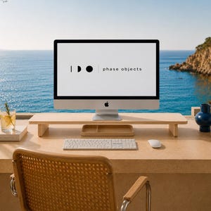 Puede incluir: Un soporte para monitor de madera clara con una superficie rectangular y dos soportes laterales, colocado sobre un escritorio. La pantalla muestra el texto "phase objects" con un gráfico de una línea vertical, un semicírculo y un círculo.