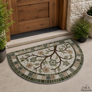 Puede incluir: Un felpudo semicircular con un patrón de estilo mosaico de ramas marrones, hojas verdes y flores de color marrón claro sobre un fondo crema, con un borde de baldosas cuadradas verdes y beige y el texto Oak & Heavens.