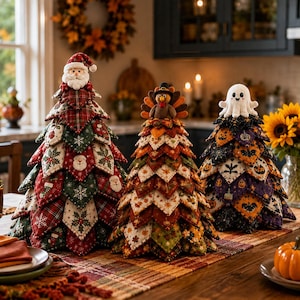 May include: Three decorative fabric trees arranged on a table. The left tree features red and green holiday patterns with a Santa topper. The centre tree displays autumn leaf prints with a turkey topper. The right tree shows Halloween motifs with a ghost topper.