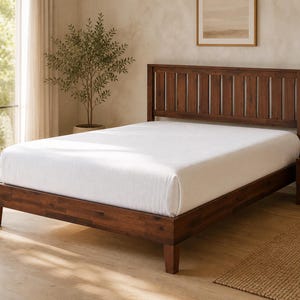May include: A dark brown wooden bed frame featuring a slatted headboard design and a low-profile base. The bed is dressed with a plain white mattress cover, showcasing a clean, structured appearance with four sturdy legs supporting the frame.