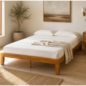 May include: A low-profile wooden bed frame with a natural light brown finish, featuring a white mattress, two white pillows, and a beige throw blanket draped across the foot of the bed, positioned on a light-colored wooden floor.
