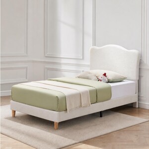 May include: A twin-sized bed frame featuring a white, textured, upholstered headboard with a curved top edge. The bed includes a light green fitted sheet, a white flat sheet, and a small decorative plush toy resting on a white pillow.
