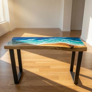 May include: A rectangular console table featuring a natural live-edge wood slab top integrated with a blue and white resin pour that mimics ocean waves. The table is supported by two black metal U-shaped legs, providing a stable base for the piece.