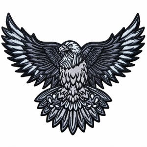 May include: An embroidered patch featuring a bald eagle in flight with wings fully spread. The design uses a monochromatic color palette of black, white, and various shades of gray to define the feathers, sharp beak, and talons of the bird.