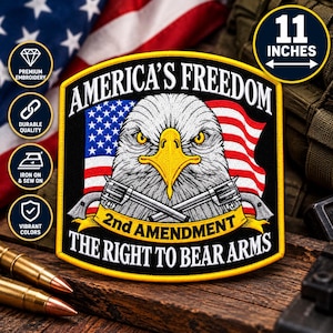 May include: A shield-shaped embroidered patch measuring 11 inches wide. It features a bald eagle, an American flag, and two crossed revolvers. The text reads: AMERICA'S FREEDOM, 2nd AMENDMENT, and THE RIGHT TO BEAR ARMS in white and yellow.