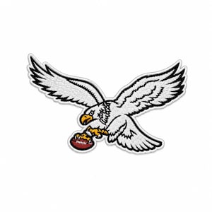 May include: An embroidered patch featuring a white eagle with black outlines and a yellow beak and talons. The eagle is depicted in flight with wings spread wide, clutching a brown American football with white laces in its sharp talons.