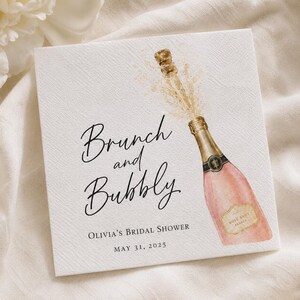 Puede incluir: Una tarjeta de invitación cuadrada de color blanco con una ilustración en acuarela de una botella de champán rosado abriéndose. El texto dice Brunch and Bubbly, Olivia's Bridal Shower y May 31, 2025, en fuentes script y serif negras sobre papel texturizado.