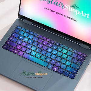 Può includere: Un computer portatile grigio scuro con una pellicola per tastiera con un vivace motivo a nebulosa galattica viola e verde acqua. Lo schermo mostra il testo AlistairShopArt LAPTOP SKIN & DECAL su sfondo sfumato e il touchpad mostra il logo.