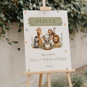 Puede incluir: Un cartel rectangular blanco sobre un caballete de madera con una pincelada verde y el nombre OLIVER. Debajo, ilustraciones en acuarela de una cebra, jirafa, elefante, mono y león con un pastel. Texto: WELCOME TO Oliver's 2nd Birthday and Baptism 07.11.2026.