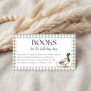 Puede incluir: Una tarjeta rectangular con un borde de cuadros vichy en color verde salvia y blanco. El texto dice: BOOKS for the birthday boy. Instead of a card, we have one small request: Please bring a book that you like best. We hope you write a special line or two, So when we read it, we think of you! Una ilustración de un pato azulón aparece a la derecha.