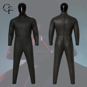 May include: A black, long-sleeved, full-body jumpsuit featuring a high collar and vertical quilted stitching throughout. The garment is displayed on a mannequin from both the front and back views, showcasing a uniform texture and a central back zipper.