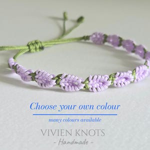 May include: A bracelet featuring a series of light purple knotted leaf-like shapes woven onto a thin olive green cord. The text "Choose your own colour", "many colours available", and "VIVIEN KNOTS - Handmade -" is printed below the bracelet.