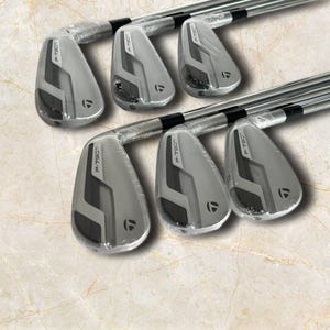 Puede incluir: Un juego de seis hierros de golf TaylorMade P-790 Ti con cabezas de color gris met&aacute;lico y detalles en negro. Cada cabeza de palo est&aacute; parcialmente envuelta en pl&aacute;stico protector transparente, mostrando el nombre P-790 Ti y el logo de TaylorMade.