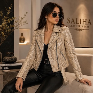 May include: A beige and brown snakeskin-patterned leather motorcycle jacket with a notched lapel, silver-tone metal zips, and a buckled belt at the hem. The jacket features long sleeves, a front zip closure, and a structured, fitted silhouette.