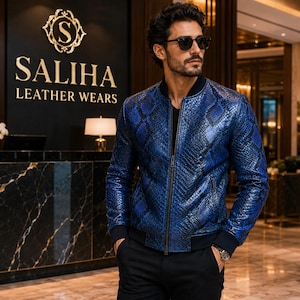 Peut inclure: Un blouson aviateur en cuir bleu et noir à motif peau de serpent, doté d'une fermeture éclair frontale, d'un col côtelé noir et de poignets côtelés noirs. La veste présente une finition texturée et est portée sur un haut noir avec un pantalon noir.