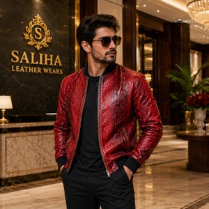May include: A red bomber jacket with a snakeskin texture pattern, featuring a black ribbed collar, black ribbed cuffs, and a central metal zip. The jacket is worn over a plain black t-shirt and black trousers, paired with dark-tinted sunglasses.
