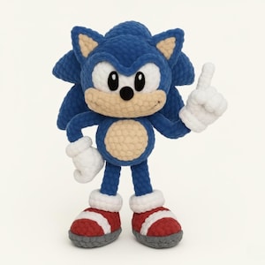 May include: A handmade crochet plush toy of the character Sonic the Hedgehog. The figure features a blue textured body, a beige muzzle and belly, white gloves, and red shoes with white straps. One hand is raised with the index finger pointing up.
