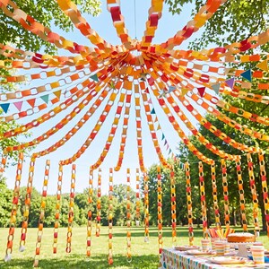 May include: A canopy of paper chains in shades of red, orange, and yellow hanging from a central point to create a tent-like structure. Small colorful triangular pennants are interspersed among the paper links, creating a festive outdoor display.