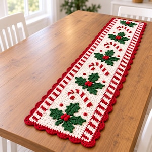 Puede incluir: Un camino de mesa rectangular de ganchillo con un centro color hueso y un patrón repetitivo de hojas de acebo verdes, bayas rojas y bastones de caramelo a rayas rojas y blancas. Tiene un borde festoneado rojo y bordes a rayas rojas y blancas.