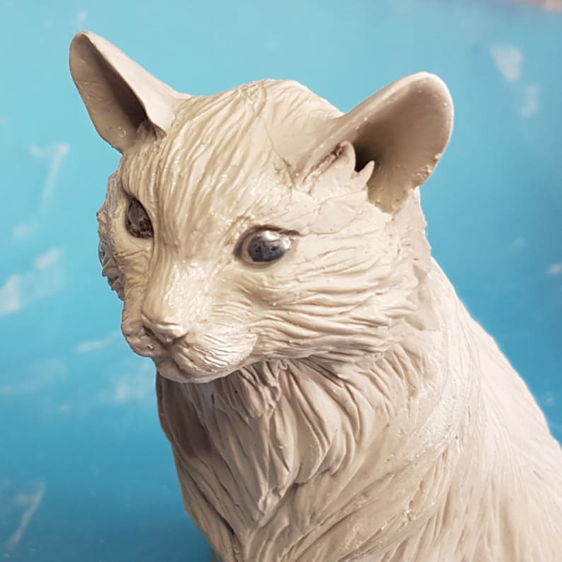 Peut inclure: Sculpture en c&eacute;ramique blanche d'un chat avec une texture de fourrure d&eacute;taill&eacute;e. Le chat a une expression r&eacute;aliste avec les yeux ferm&eacute;s et la t&ecirc;te l&eacute;g&egrave;rement inclin&eacute;e.