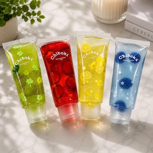 May include: Four clear squeeze tubes labeled Chiboki Decompression Toys, each filled with colored gel and themed charms. The green tube has clover shapes, the red has round red pieces, the yellow has lemon slices, and the blue has stars and spheres.