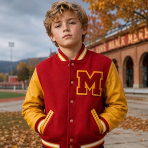 May include: A varsity jacket featuring a deep red wool body and contrasting yellow leather sleeves. The jacket includes a large yellow letter M patch on the left chest, a snap-button front closure, and striped ribbed trim at the collar, cuffs, and hem.
