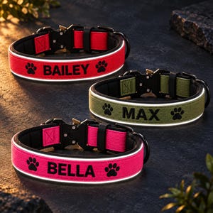 Op de afbeelding: Drie halsbanden voor huisdieren met zwarte metalen gespen en reflecterende biezen. De rode halsband is geborduurd met de naam BAILEY, de olijfgroene met MAX en de felroze met BELLA, elk geflankeerd door zwarte pootafdruk-iconen.